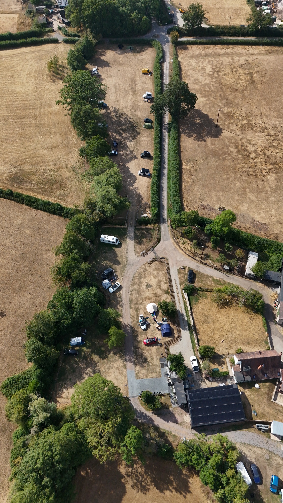 Vertical aerial view following a long farm track through geometric summer fields