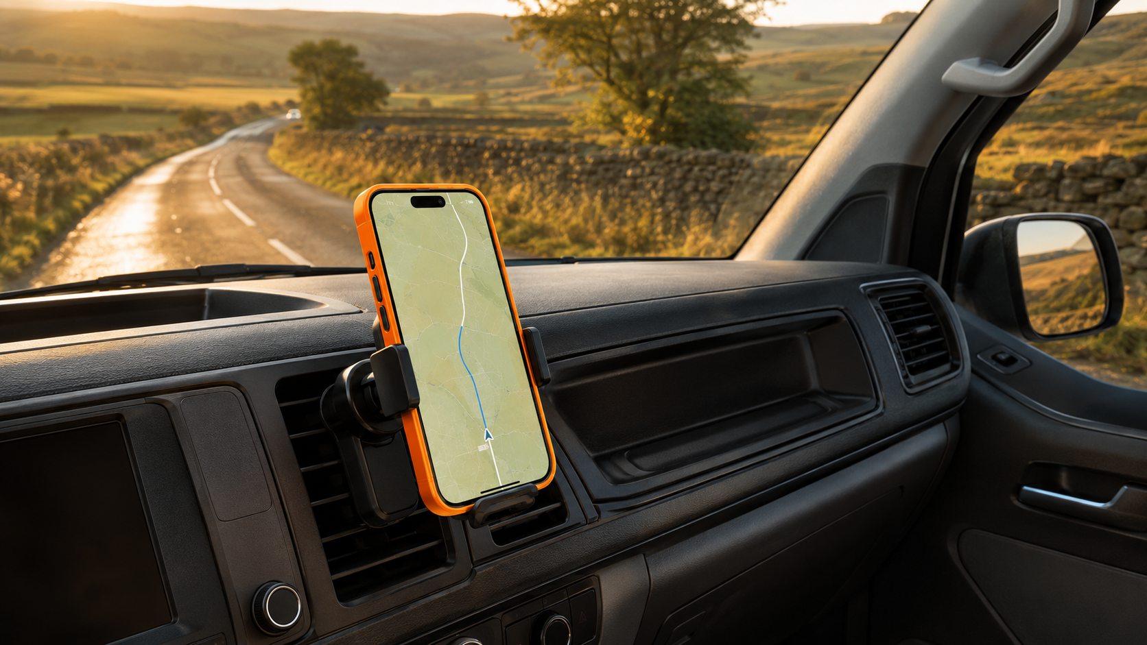 An orange iPhone mounted in the dashboard of a dark campervan at golden hour