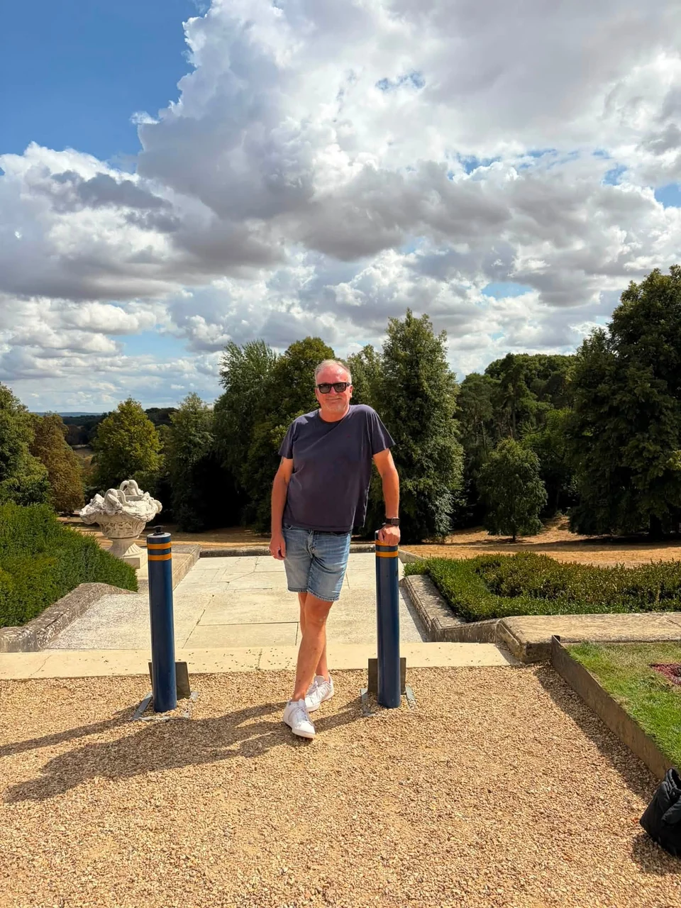 John standing on a terrace at Waddesdon Manor beneath a dramatic summer sky