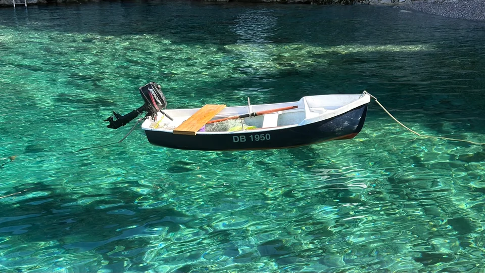 A small black and white fishing boat floating over clear turquoise water