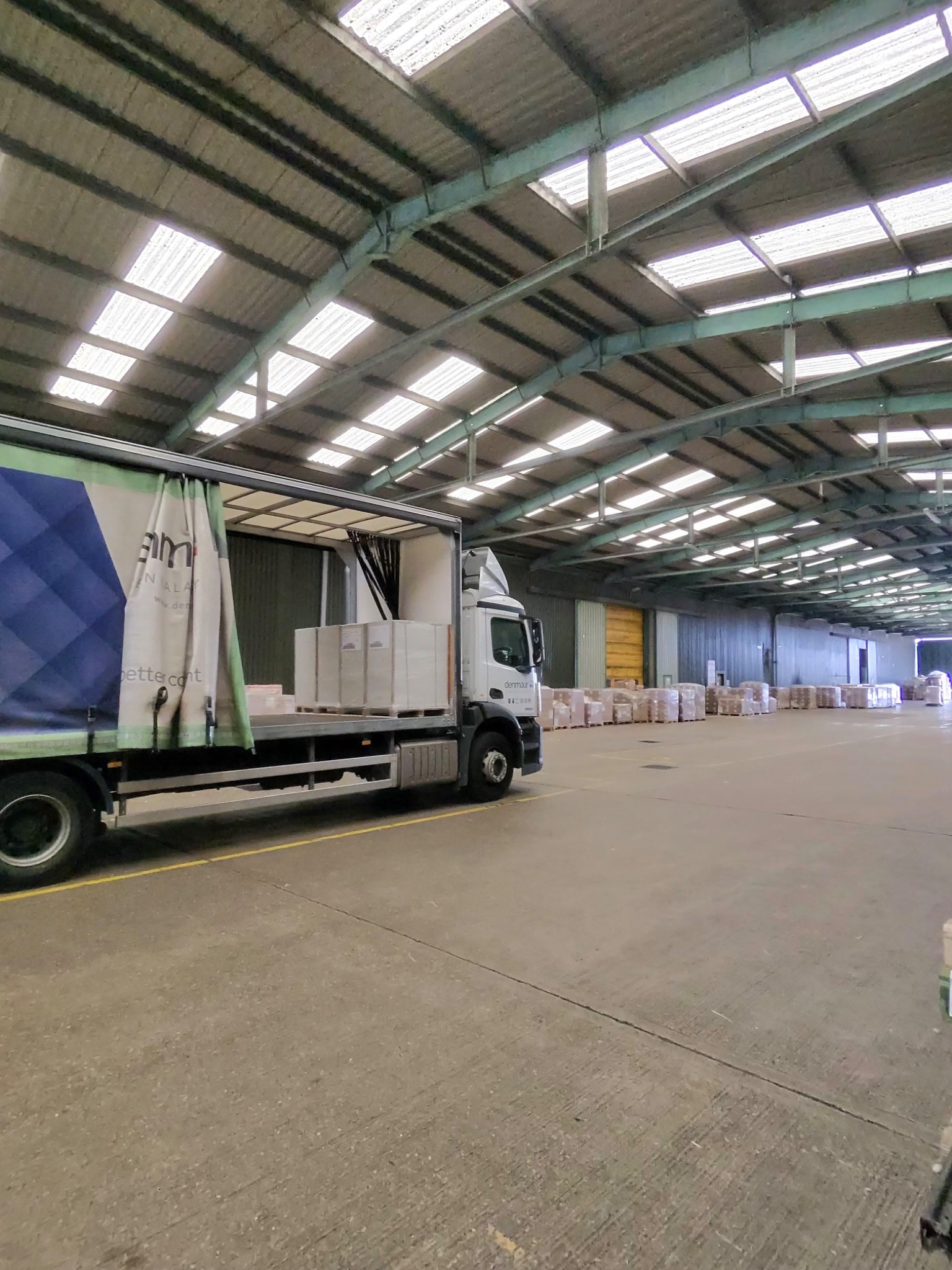 Rigid curtainsider being unloaded inside a large paper warehouse