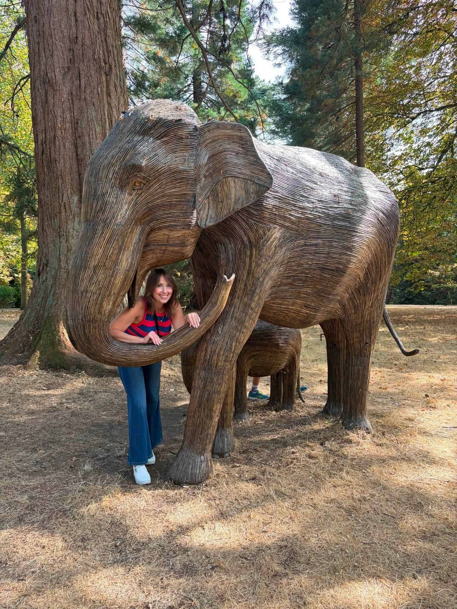 Fiona posing inside the curved trunk of a large woven elephant sculpture