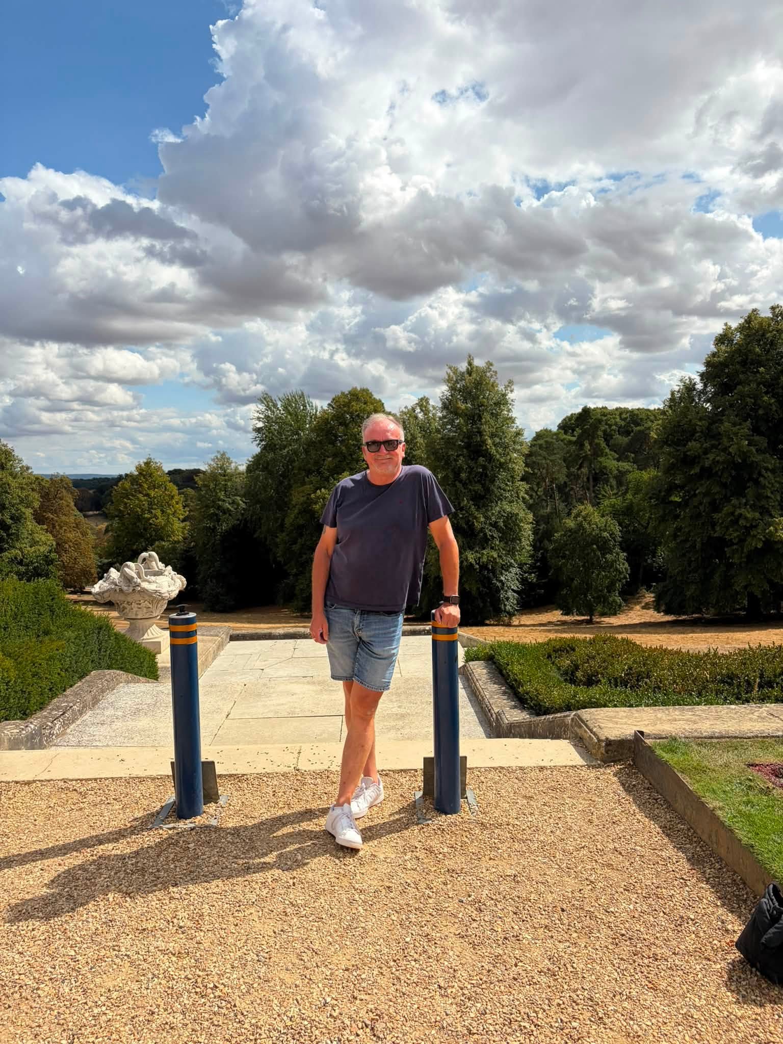 John standing on a terrace at Waddesdon Manor beneath a dramatic summer sky